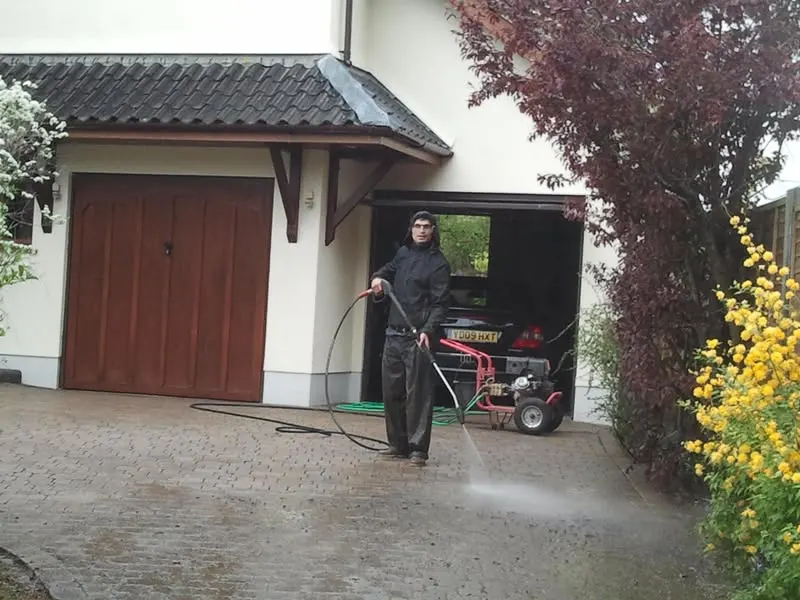 Dlažba před garáží. Průběh: pracovník čistí dlažbu před garáží rodinného domu.