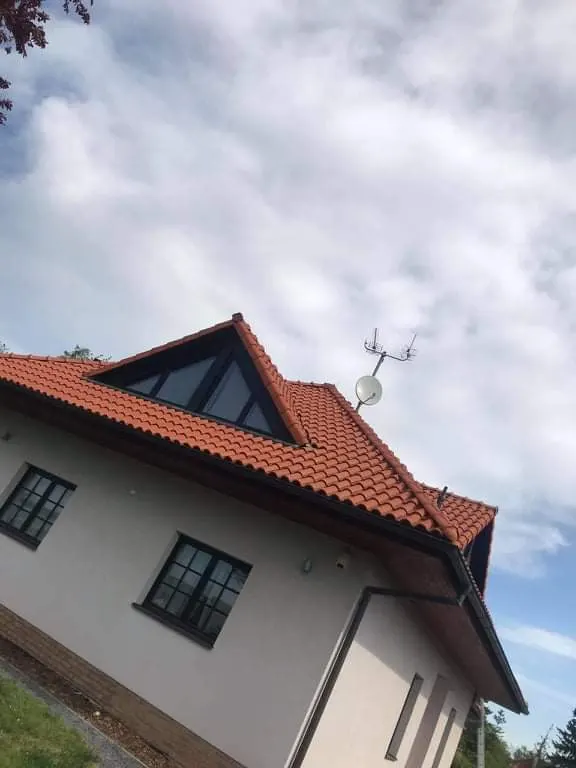 Štít a krytina. Po: štít domu s červenou krytinou při pohledu zdola.