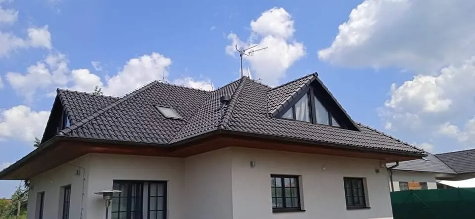 Střecha vily po dokončení. Po: vila s tmavou střešní krytinou, modrá obloha.